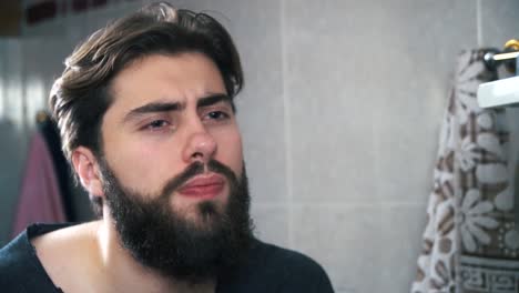 man trimming his beard in the bathroom