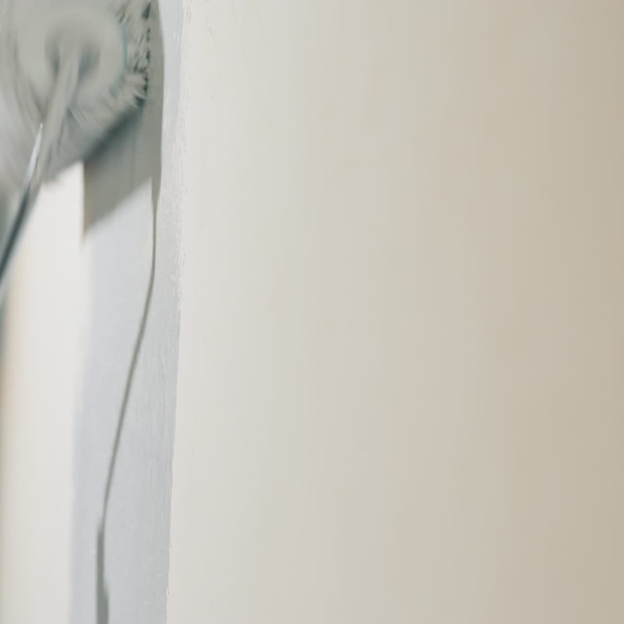 La mano de un constructor pinta la pared de la casa