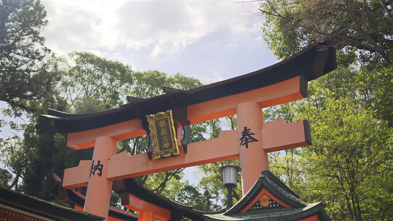 A vibrant red torii gate stands majestically among the trees, symbolizing the entrance to a sacred area. Text translation: ''Okami Shrine". Fushimi Inari, Kyoto, Japan