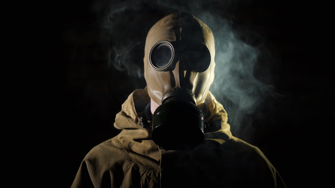 Un uomo con tuta protettiva e maschera antigas che fuma in primo piano