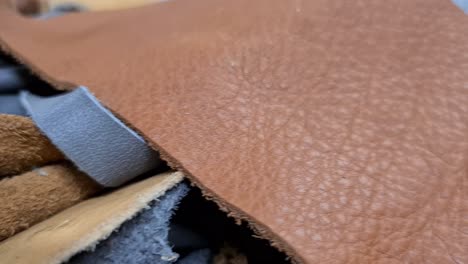 colored-leather-pieces-in-workshop,-close-motion-view