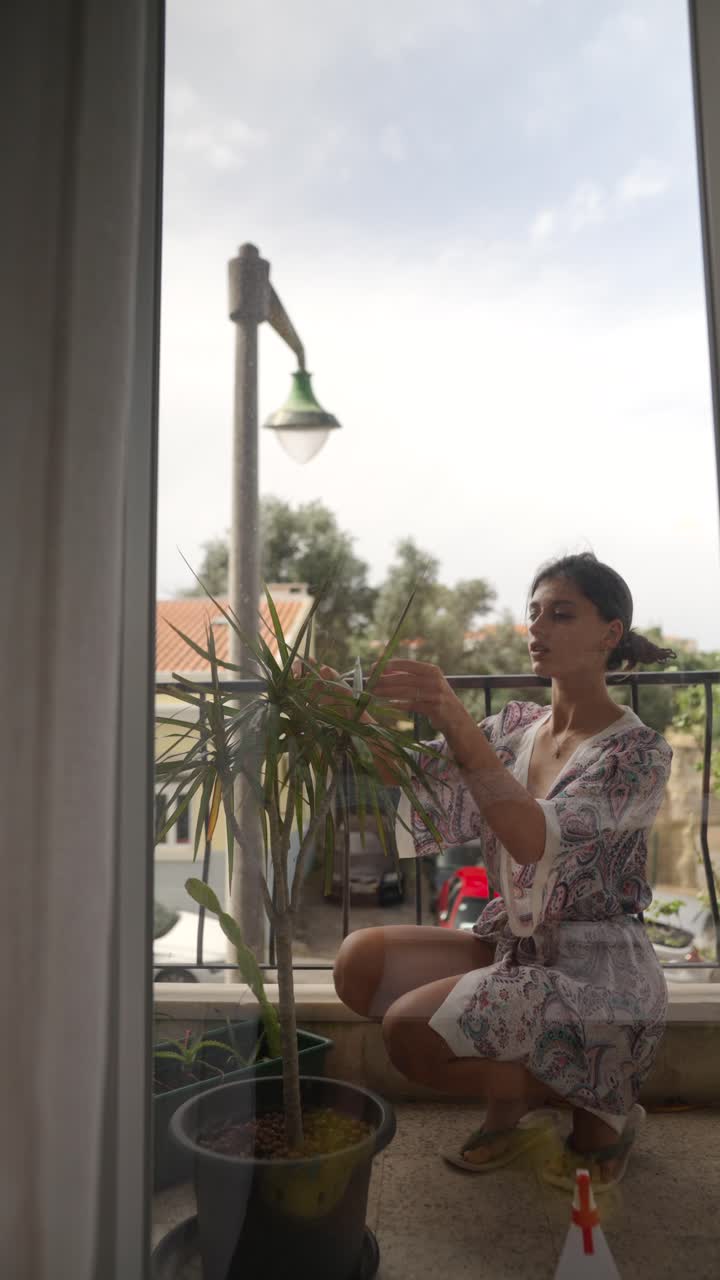Woman Caring for Houseplant on Balcony