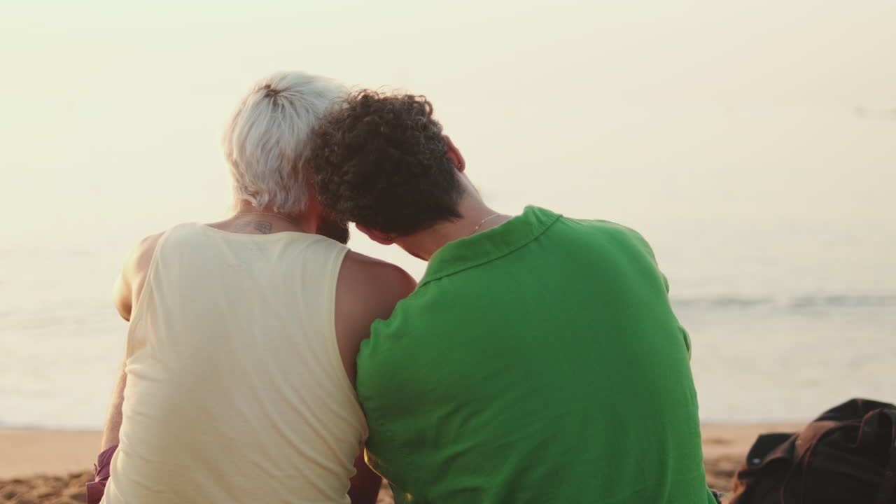 Due amici si godono il tramonto sulla spiaggia
