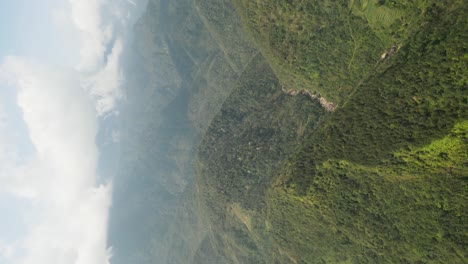 vertical - fog clouds over lush green mountains in sapa, vietnam. drone shot