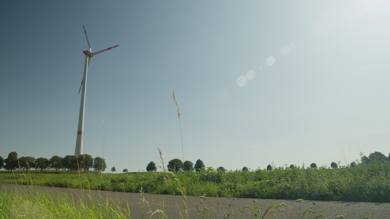 Wind turbines silhouetted against warm sunset sky, blades turning slowly in tranquil countryside