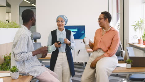 Muslim-Businesswoman,-Businesswoman-And-Young-Worker-Are-Talking-In-The-Office-While-Drinking-Coffee