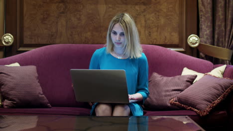 Beautiful-woman-sitting-on-luxury-sofa-and-working-on-notebook-computer