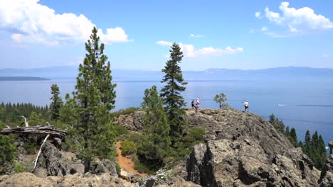 Travelers-view-a-vast-lake,-ocean-or-inlet-on-a-rocky-shoreline-on-a-sunny-day