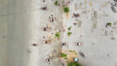 海岸近くの漁船と漁師が網を修理している上の景色