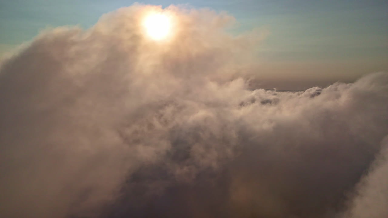 Sunset aerial view of soft cloud cover with sunlight shining through the mist
