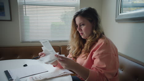 woman sorting through bills and receipts at kitchen table in the afternoon, stressed out over budgeting and finances