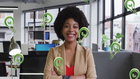 Animation-of-lightbulb-icons-over-smiling-african-american-businesswoman-in-office