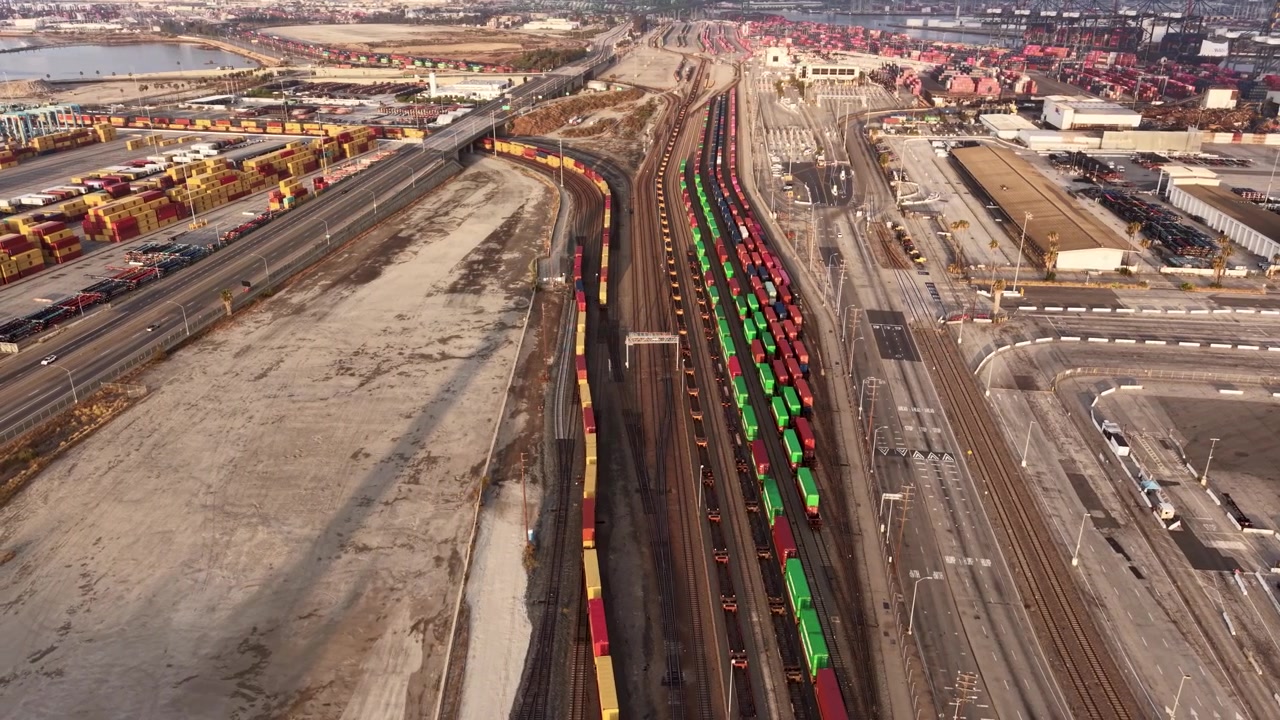 Ein langer Güterzug fährt in Richtung des Hafens von Los Angeles und transportiert Container aus dem ganzen Land. Die immense Länge des Zuges aus der Luft betrachtet.