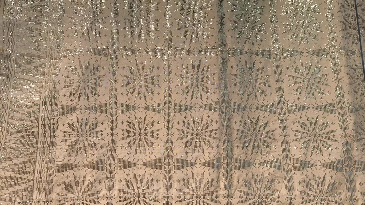 Primo piano dettagliato di lussuoso tessuto Songket. L'intricato ricamo dorato brilla sulla superficie tessuta a mano. Questo prestigioso tessuto malese è riservato alle occasioni più speciali.