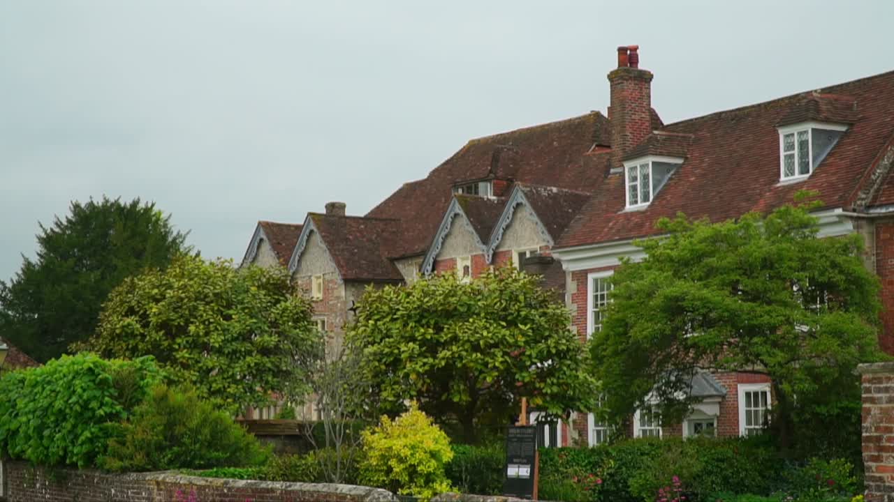 View of the historic Mompesson House in Salisbury, England, with red-brick facade, gabled rooftops, and lush garden surroundings in a traditional English setting.