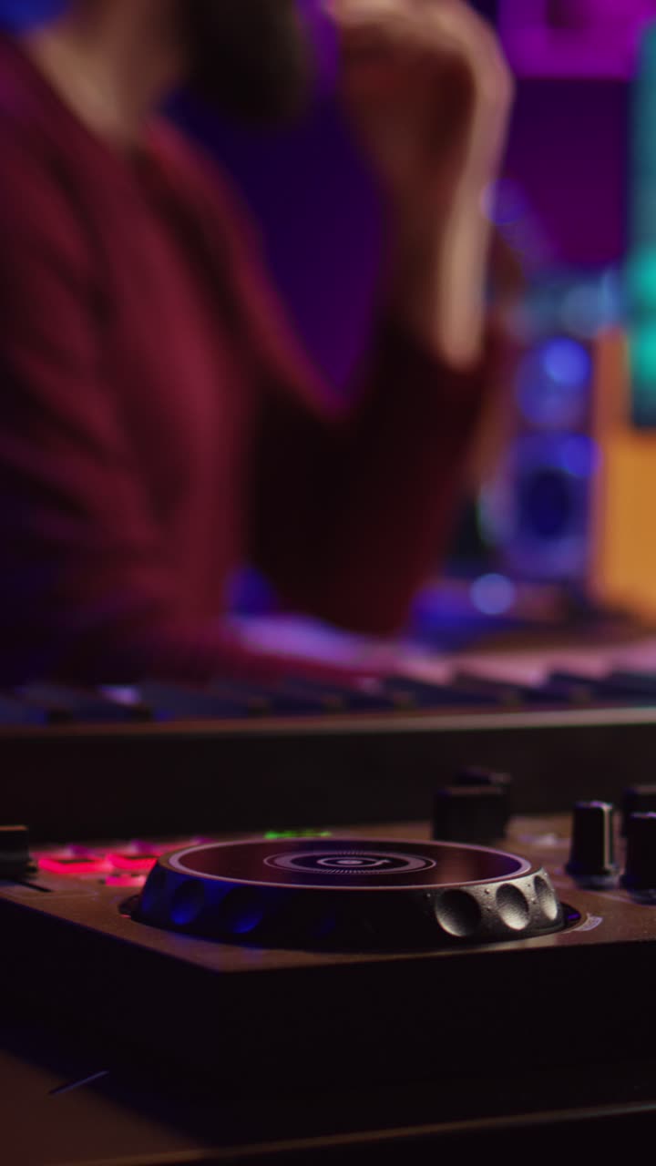 Uomo che produce musica in uno studio domestico con un mixer da DJ e una tastiera