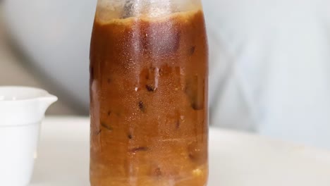 watch as iced coffee blends with milk inside a glass bottle, creating a swirling effect.