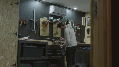 man waxing alpine skis on garage workbench for winter preparation