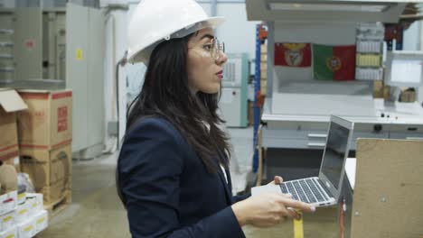 un gerente de proyectos asiático serio caminando con una computadora portátil en la fábrica