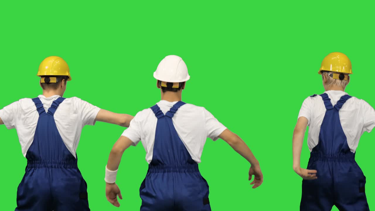 단단한 모자를 입은 세 명의 남성 건설 노동자가 녹색 화면, 크로마 키에서 카메라에 등으로 춤을 추고 있습니다.