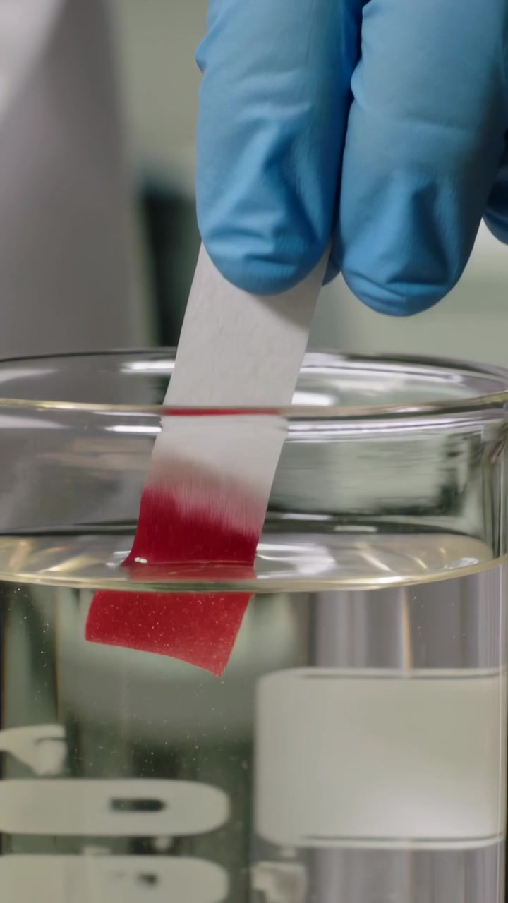 Vertical video: Cutting strip with scissors, tech in blue gloves dipping into beaker testing liquid