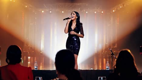 woman singing on stage with microphone