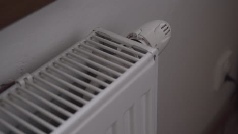 turning on heating or radiator thermostat, hand closeup, full power, wasting money