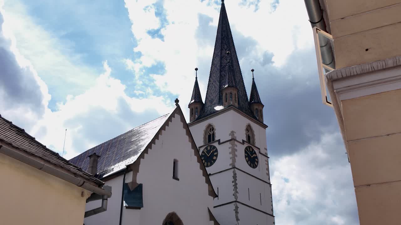 Scenic view of the Lutheran Cathedral of Saint Mary in Sibiu, nestled between neighboring historic buildings in the old town