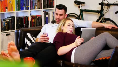 couple using mobile phone and digital tablet on sofa