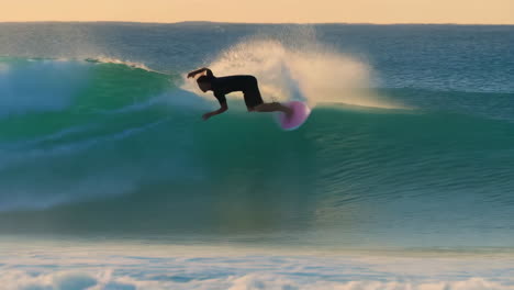 surfer riding a large ocean wave at sunset