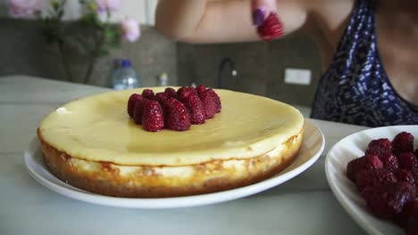 Close-Up-view-of-woman's-hands-adoring-and-decorating-the-top-of-the-cake-with-raspberries