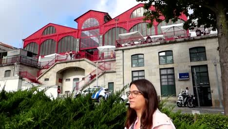 Tourist-walks-in-front-of-Ferreira-Borges-Market-and-Police-Station,-Porto