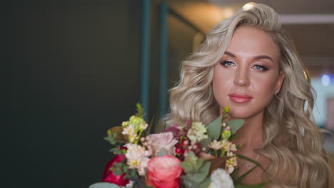 woman holds fresh bouquet walking along hallway of hotel