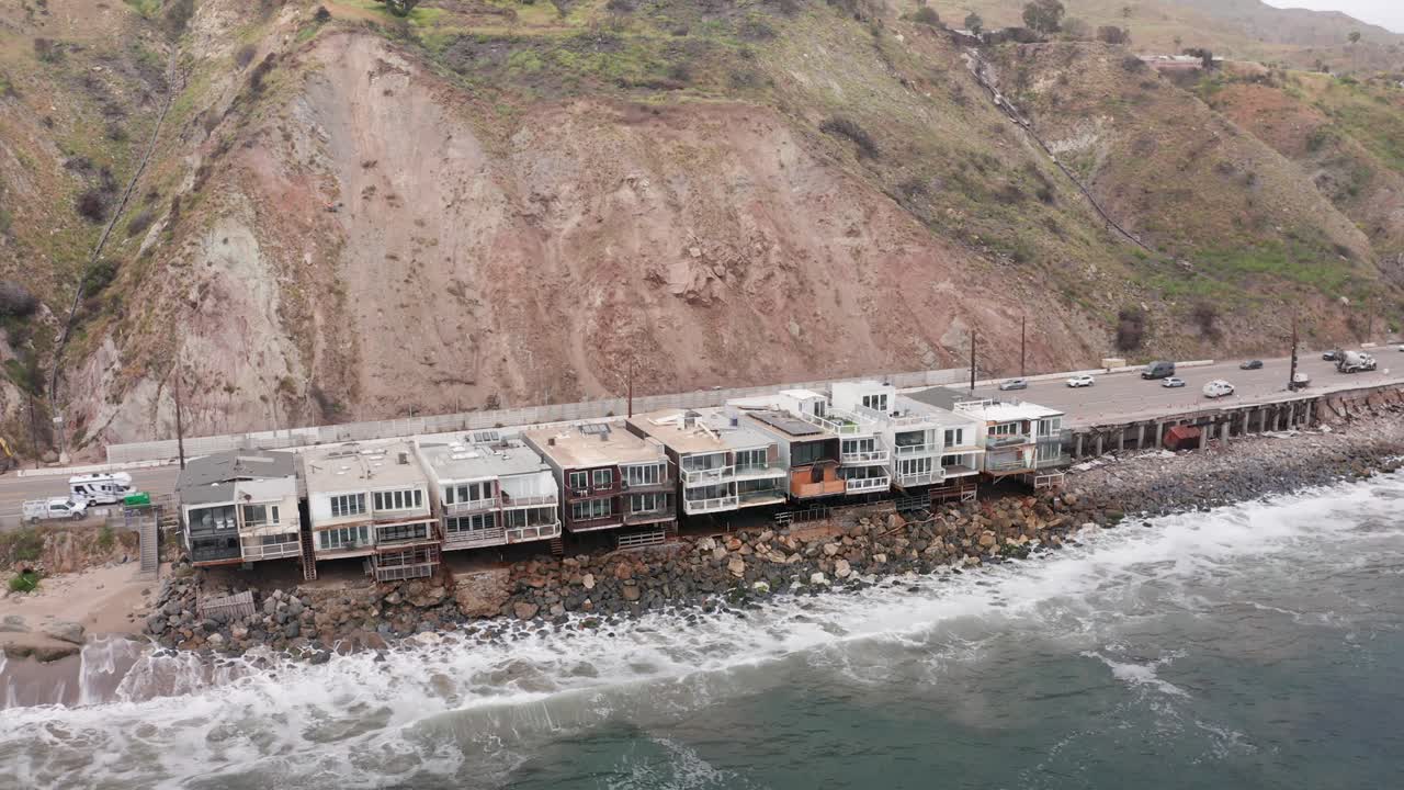 Aerial close-up panning shot of beachfront homes that survived the Palisades Fire in Malibu, California. 4K