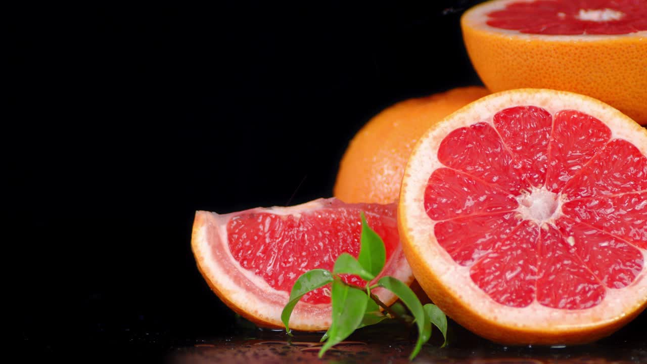 Drops of water falling on a ripe juicy grapefruit with leaves.
