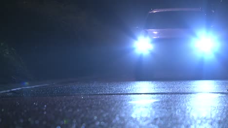 car passing with headlights at night raining