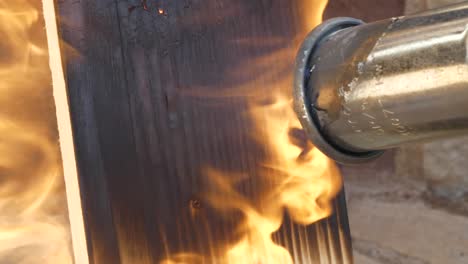 soplete de gas quemando tablones de madera de pino, cerrar