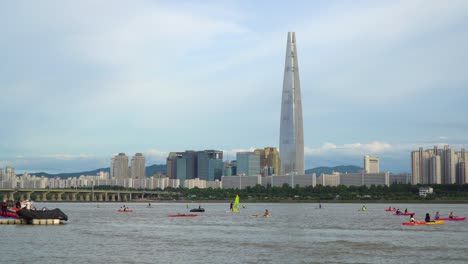 Escena-De-Personas-En-Actividades-De-Deportes-Acuáticos-En-El-Río-Han-Con-Lotte-World-Tower-En-El-Paisaje-Urbano-De-Seúl,-Corea-Del-Sur