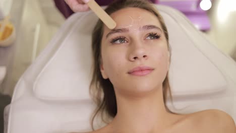 woman getting eyebrow waxing treatment at a beauty salon