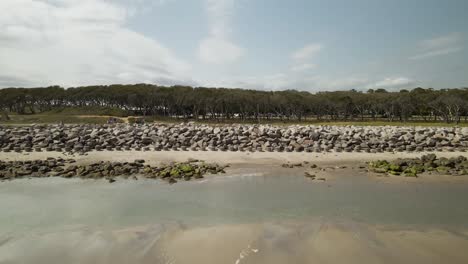 Kure-beach-North-Carolina-aerial-flying-over-seawall-towards-forest