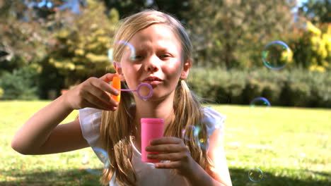 young girl blowing into a bubble wand