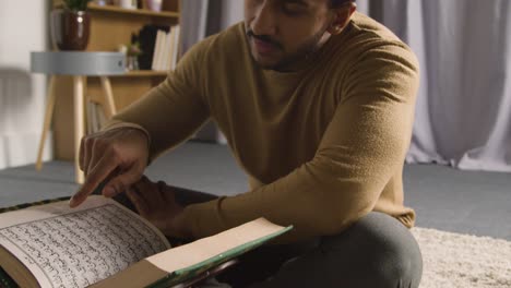 muslim man at home sitting on floor and reciting from the quran 3