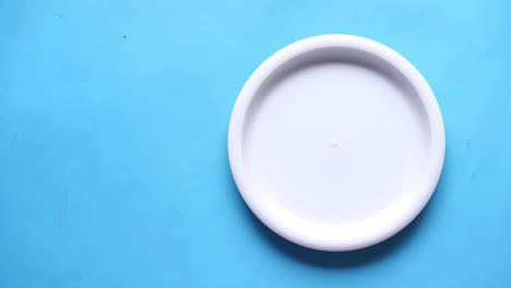 poniendo un plato vacío de colores en la mesa