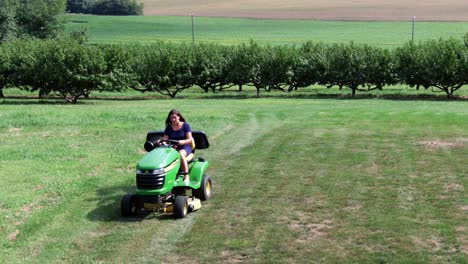 young hispanic woman mowing lawn on tractor cutter