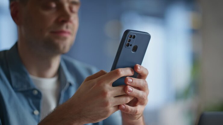 Nahaufnahme: Konzernmanager textet am Mobiltelefon im Büro. Lächelnder Geschäftsmann