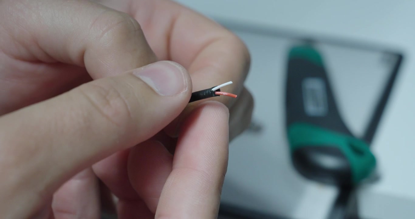 Primo piano di un cavo con isolamento rimosso e fili scoperti, che mostra rischi elettrici, danni e problemi di sicurezza