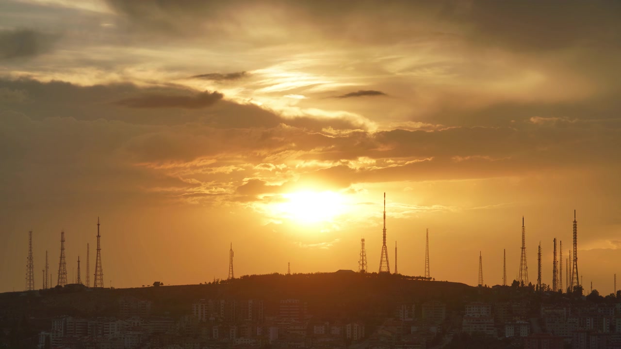 Pôr do Sol Dourado Sobre o Horizonte da Cidade com Torres de Comunicação
