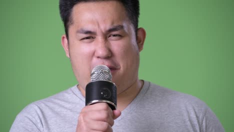 초록색 배경에 젊은 잘생긴 과체중 아시아인