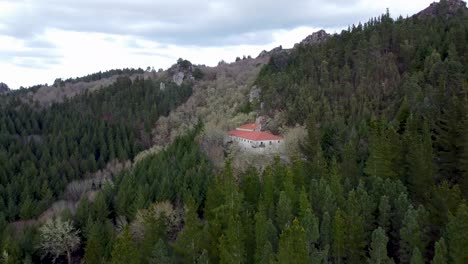 Spanisches-Kloster,-Versteckt-Zwischen-Hohen-Grünen-Kiefern-An-Bewölkten-Tagen,-Breite-Antenne