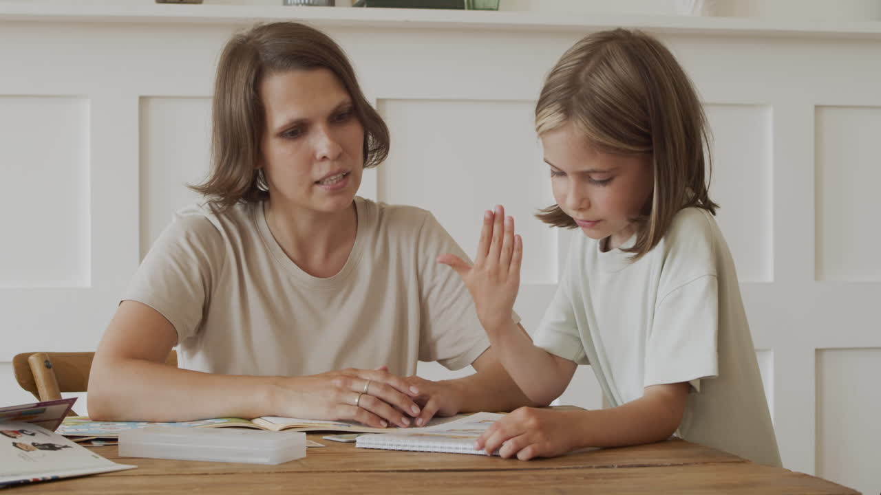una linda niña rubia hace su tarea en un cuaderno con la ayuda de su madre